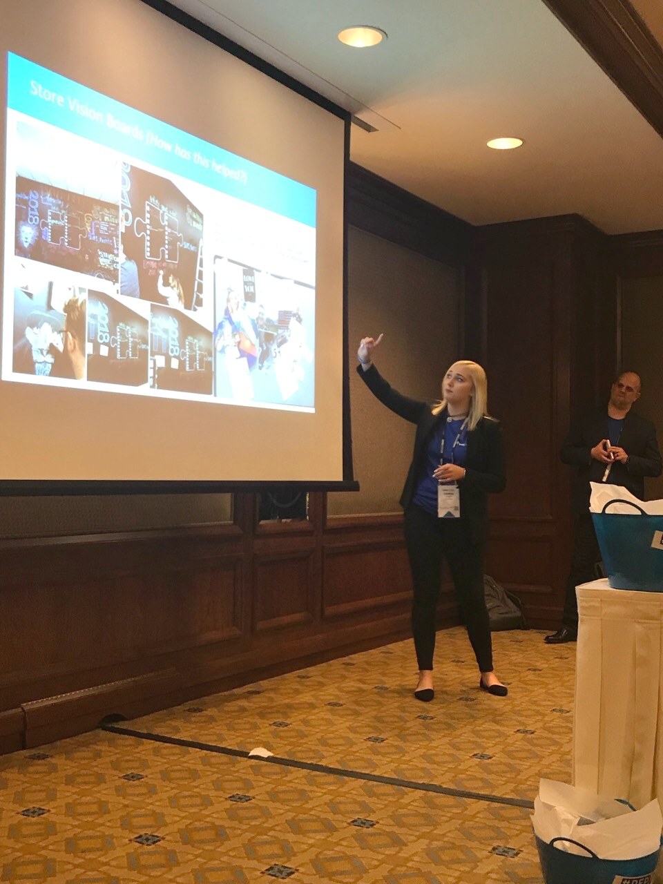 Lindsey Lorette presenting at an AT&T Authorized Retail leadership convention, beside a slide of store vision boards