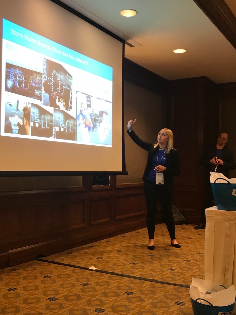 Lindsey Lorette presenting at an AT&T Authorized Retail leadership convention, beside a slide of store vision boards
